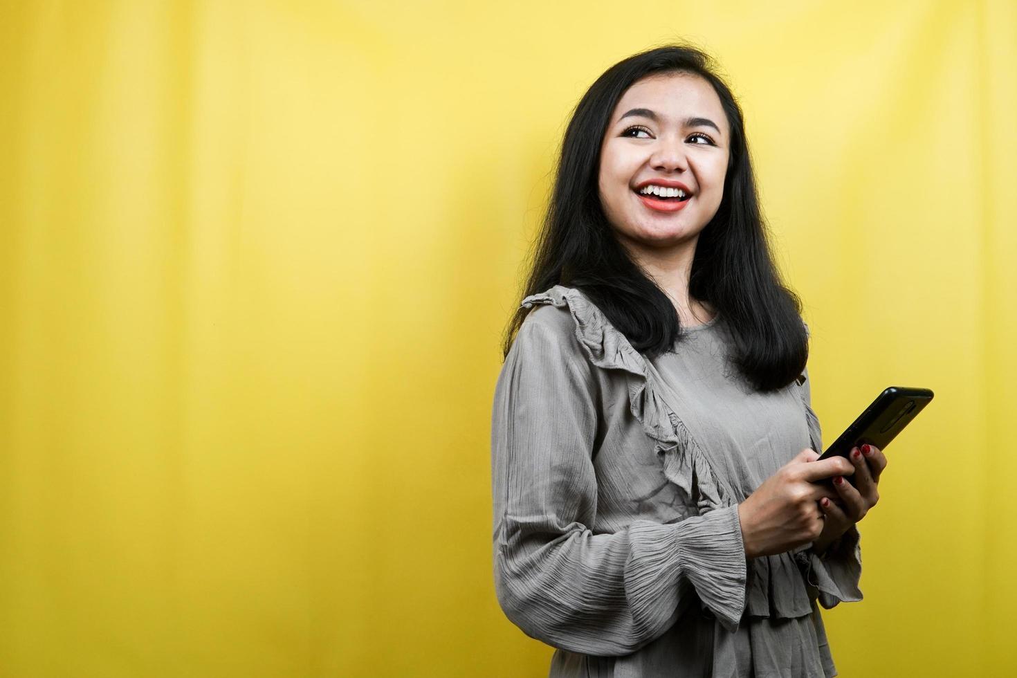 Hermosa mujer joven con las manos sosteniendo el teléfono inteligente, mirando el espacio vacío, promocionando el producto, presentando algo, publicidad, aislado foto