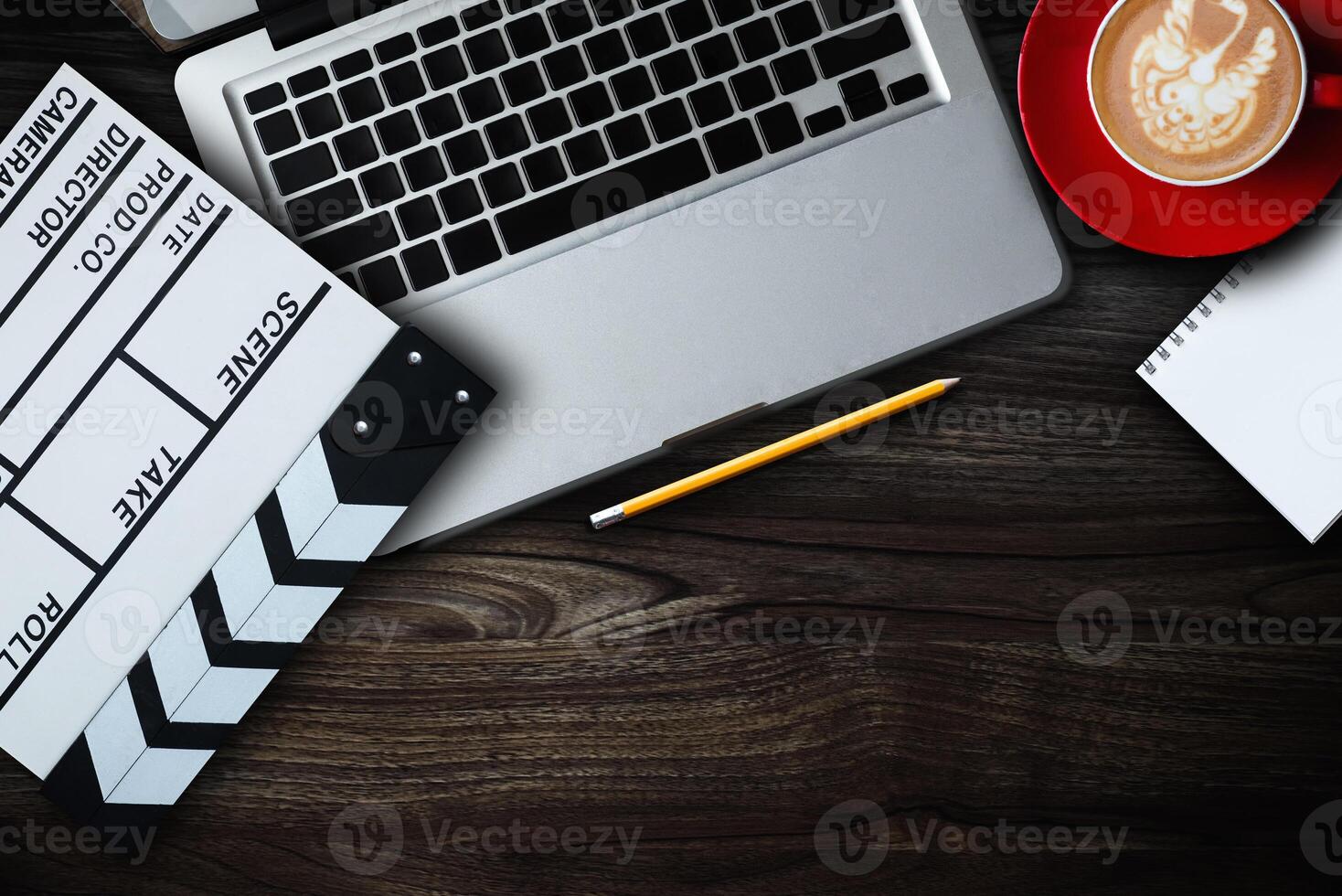 office stuff with Movie clapper, laptop, smartphone, tablet, coffee cup, pen, notepad and documents on the wood table top view shot. photo