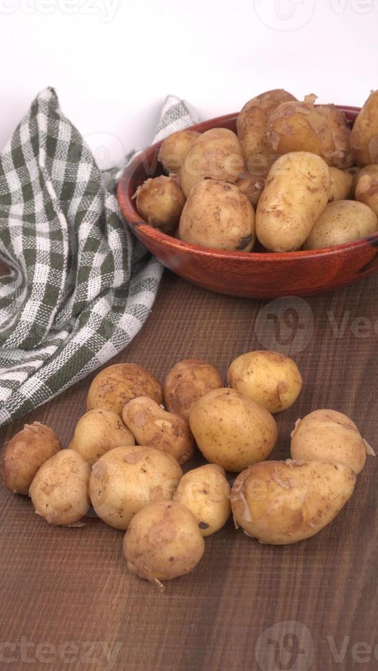 Fresh small potatoes for cooking in a wooden bowl. With copy space  on white background. photo