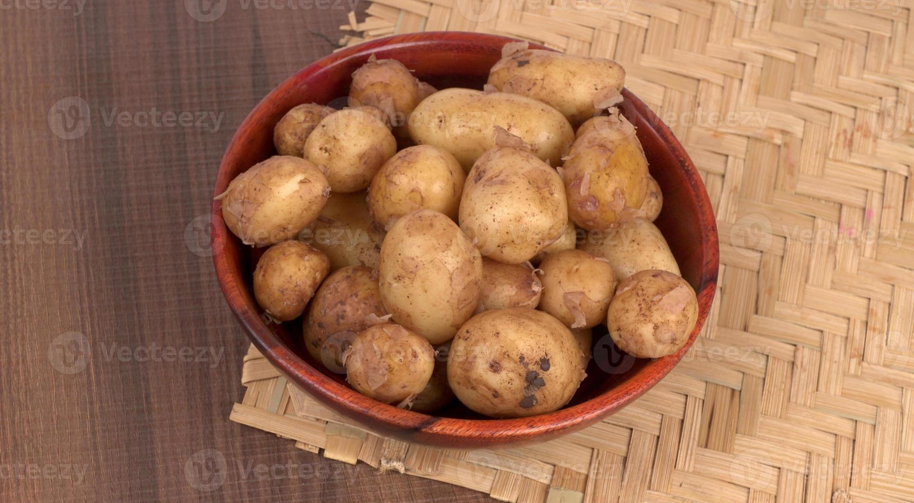 Fresh small potatoes for cooking in a wooden bowl. With copy space  on white background. photo