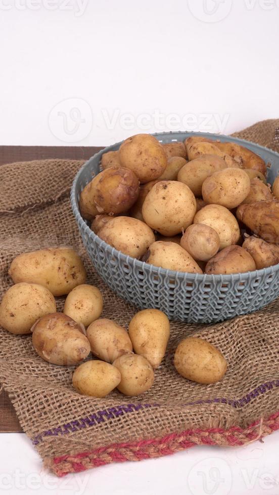 Fresh small potatoes for cooking in a wooden bowl. With copy space  on white background. photo