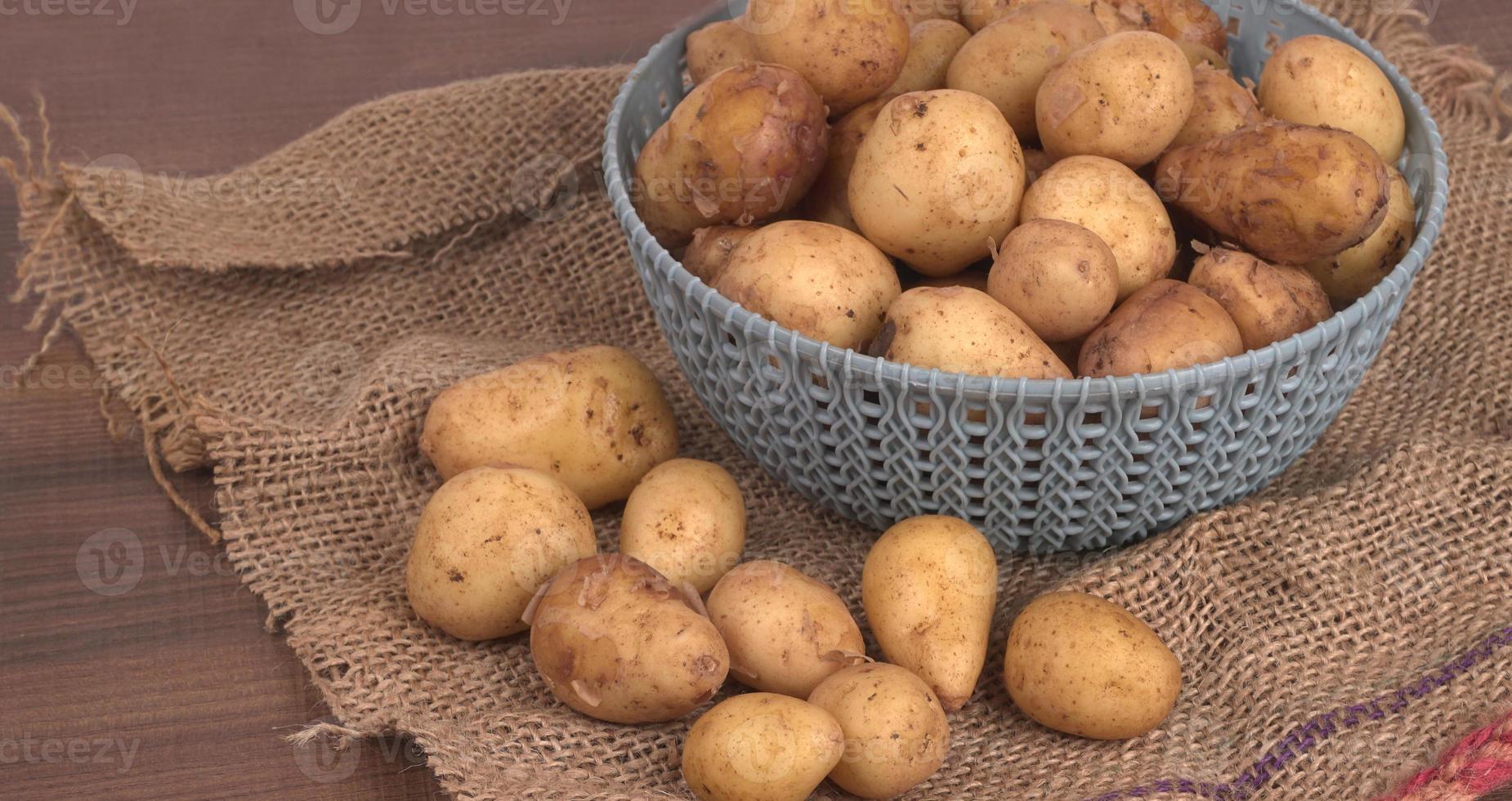 Fresh small potatoes for cooking in a wooden bowl. With copy space  on white background. photo