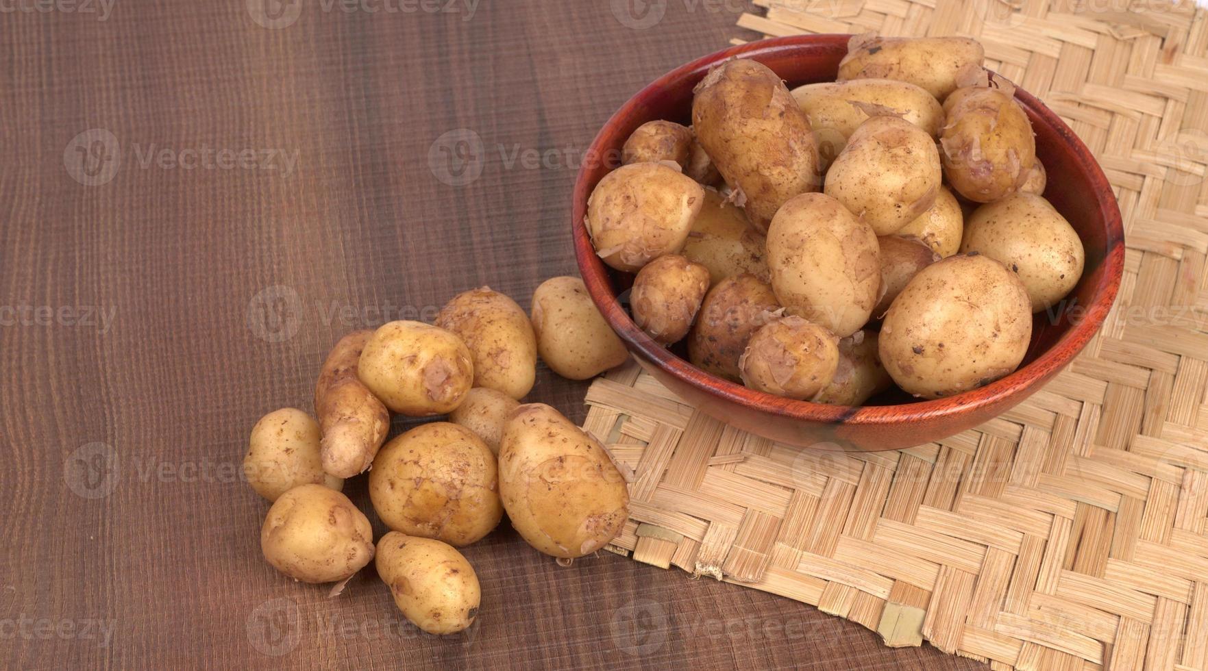 patatas pequeñas frescas para cocinar en un cuenco de madera. con espacio de copia sobre fondo blanco. foto