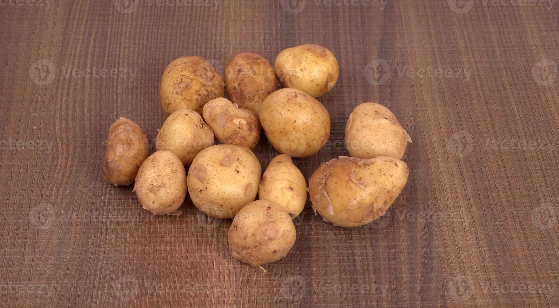 Fresh small potatoes for cooking in a wooden bowl. With copy space  on white background. photo