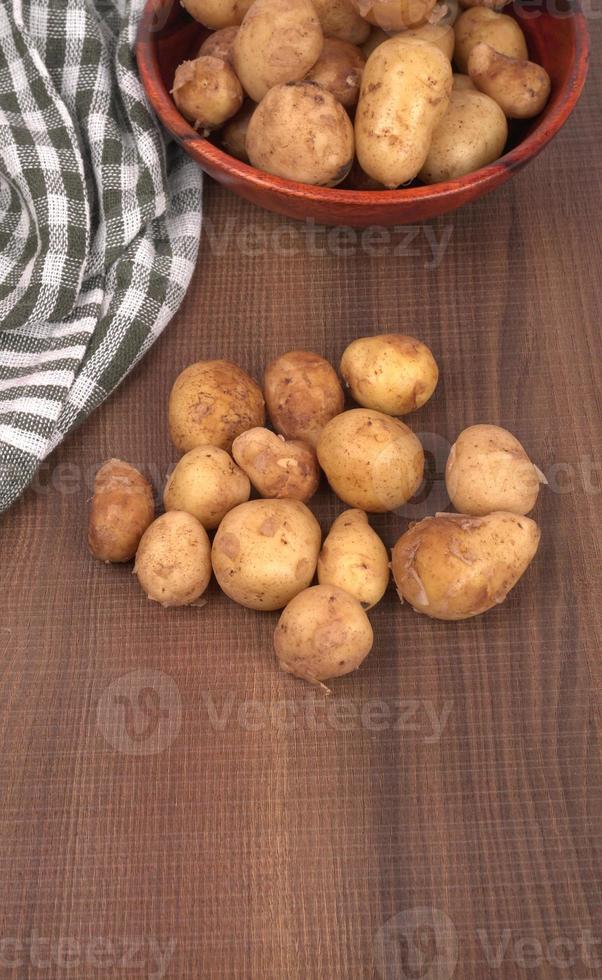 Fresh small potatoes for cooking in a wooden bowl. With copy space  on white background. photo