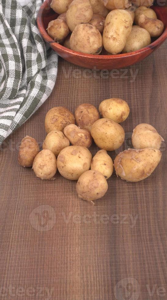 Fresh small potatoes for cooking in a wooden bowl. With copy space  on white background. photo