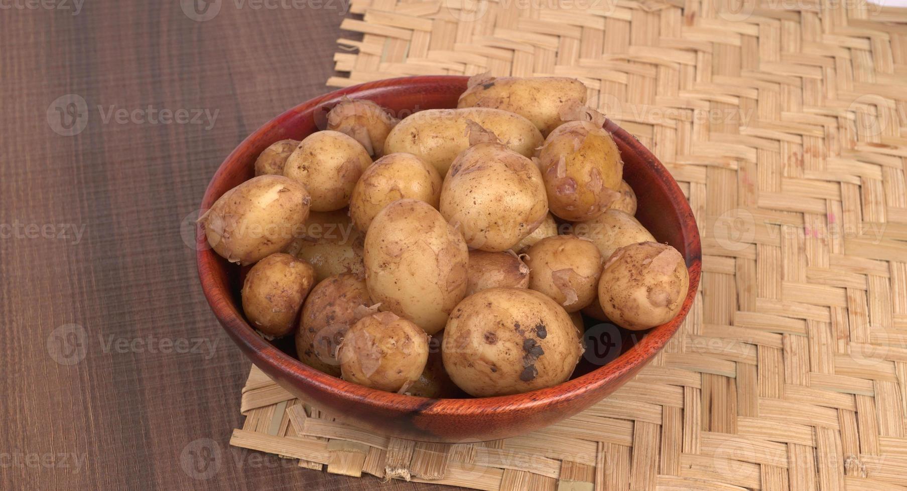 Fresh small potatoes for cooking in a wooden bowl. With copy space  on white background. photo