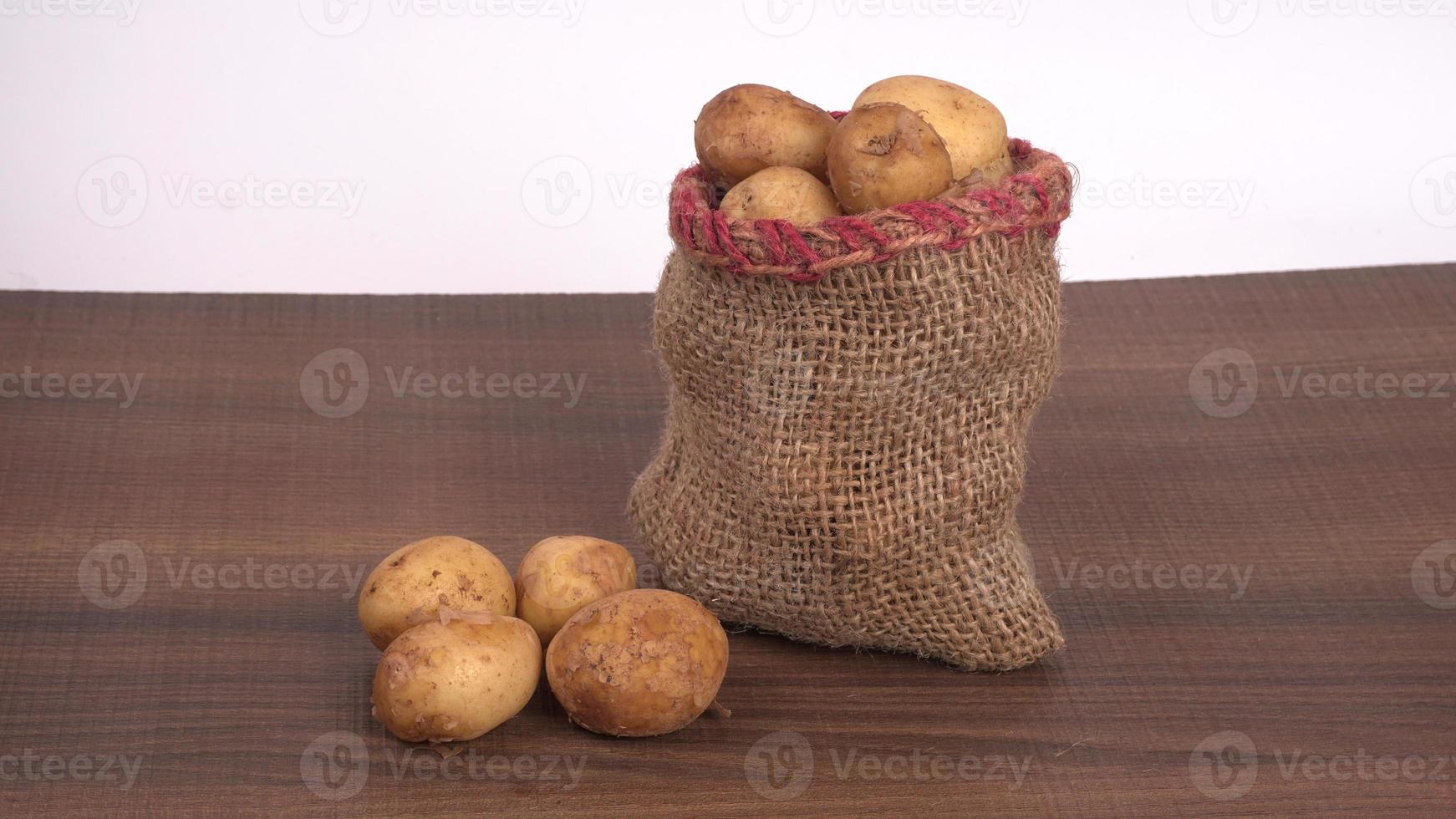 patatas pequeñas frescas para cocinar en un cuenco de madera. con espacio de copia sobre fondo blanco. foto