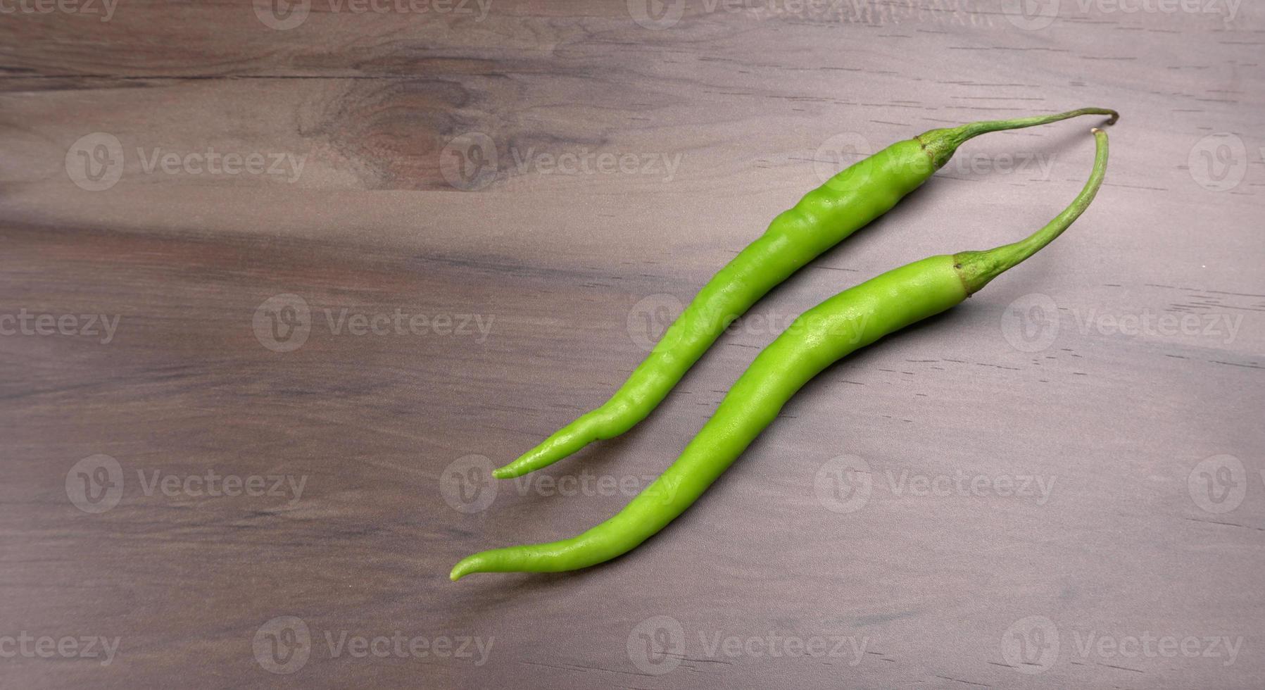 Fresh long Indian green chillies on wooden background. photo