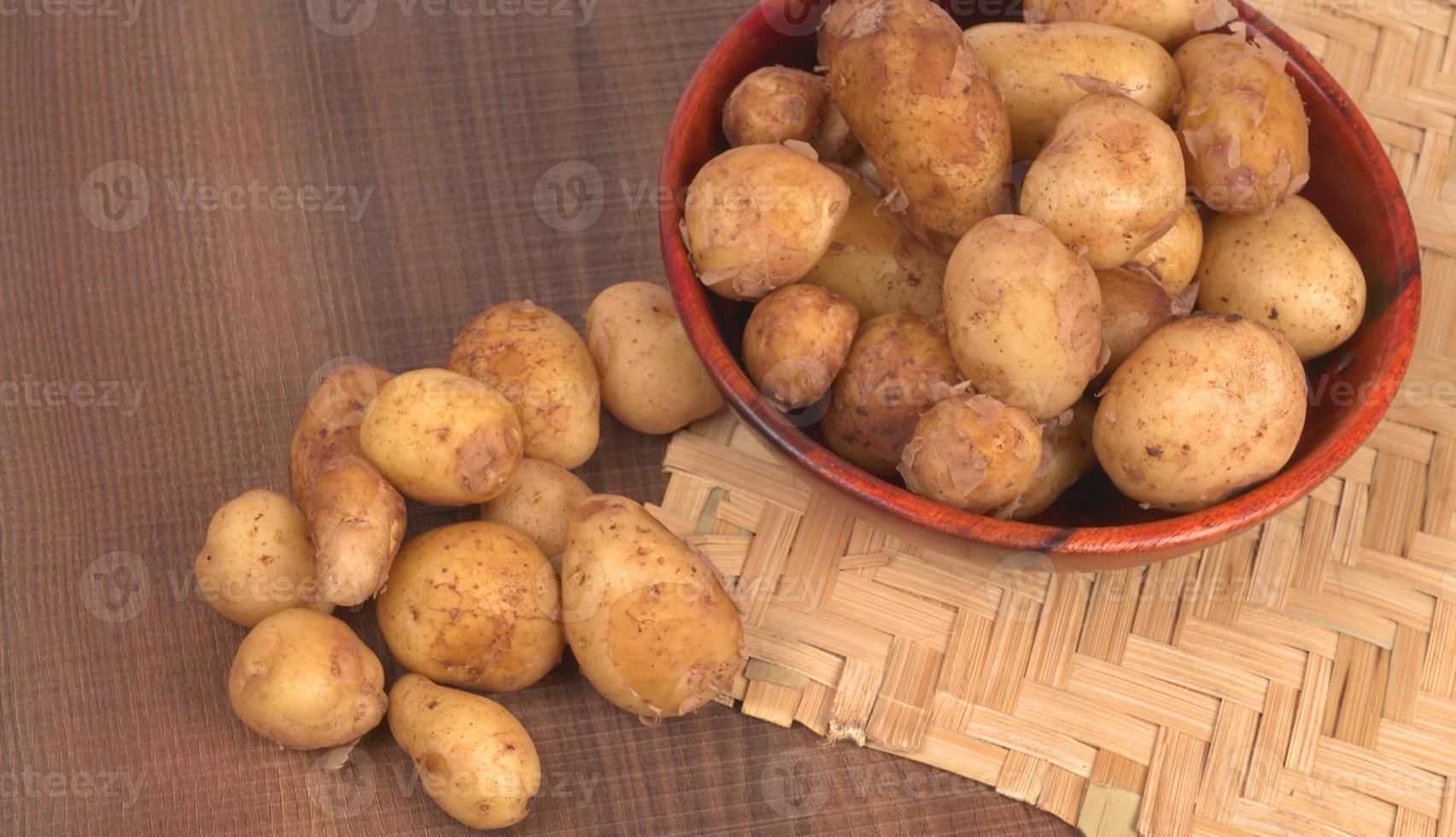 Fresh small potatoes for cooking in a wooden bowl. With copy space  on white background. photo