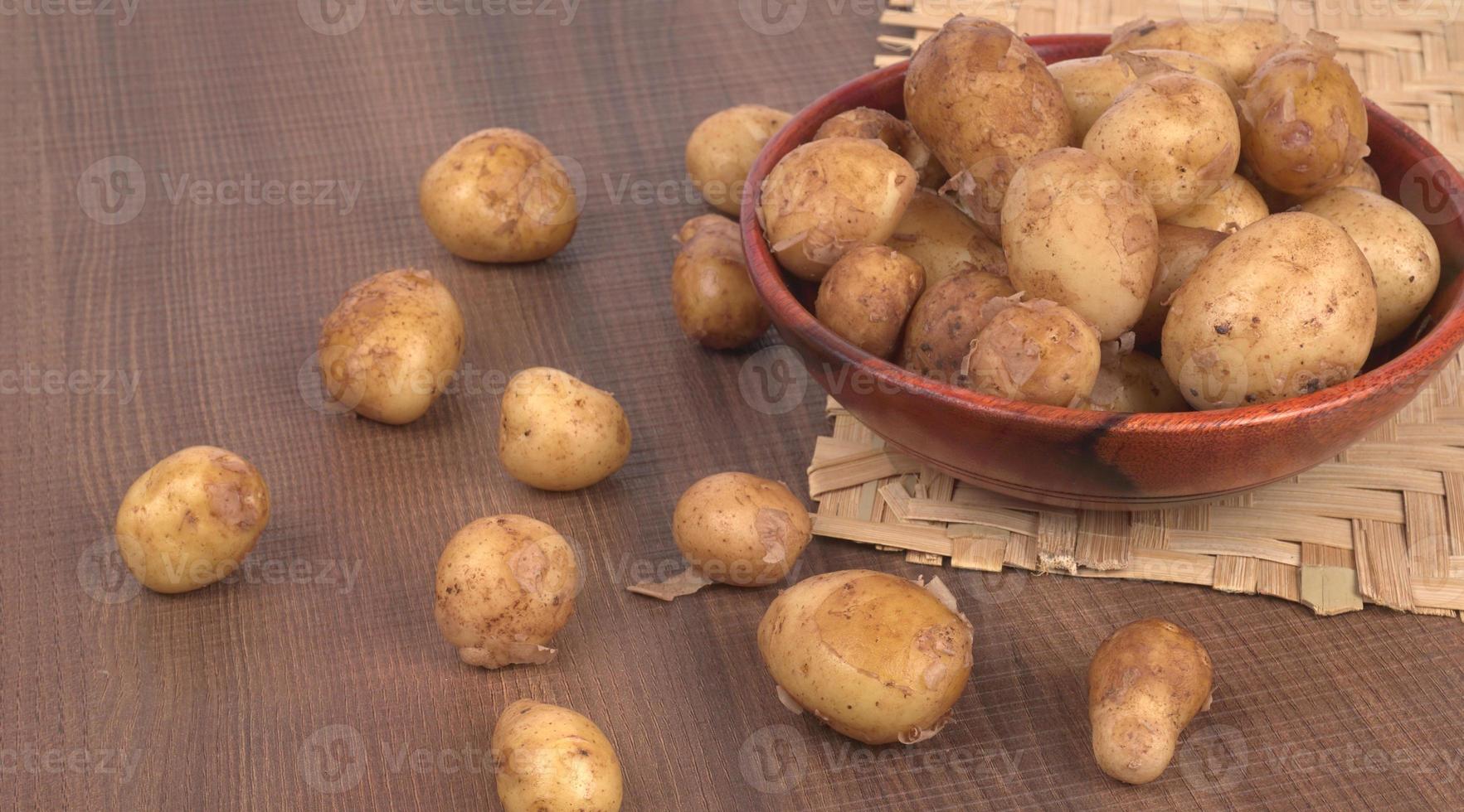 Fresh small potatoes for cooking in a wooden bowl. With copy space  on white background. photo