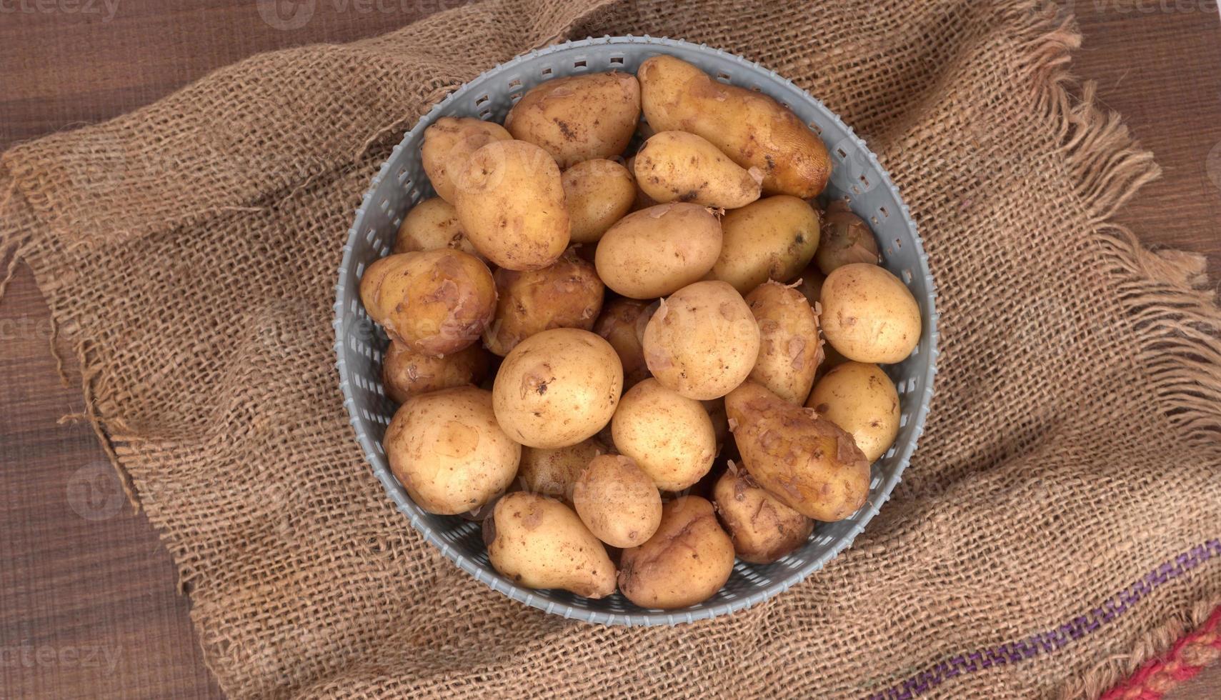 Fresh small potatoes for cooking in a wooden bowl. With copy space  on white background. photo