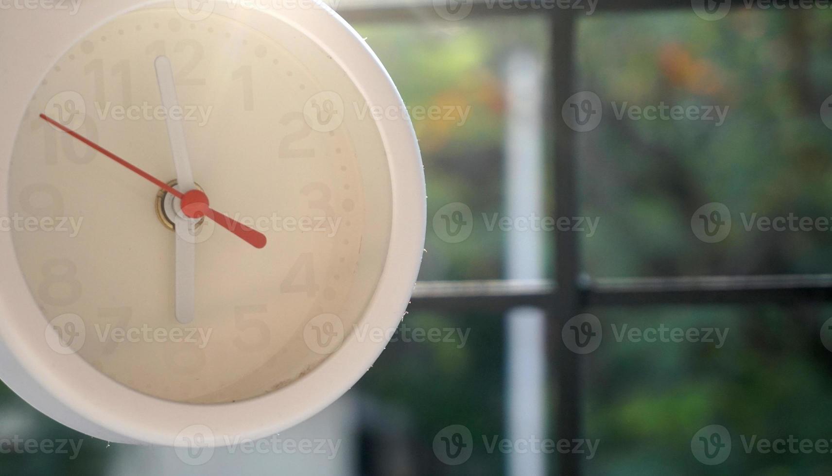 A closeup shot of a white clock with arrows showing time. photo