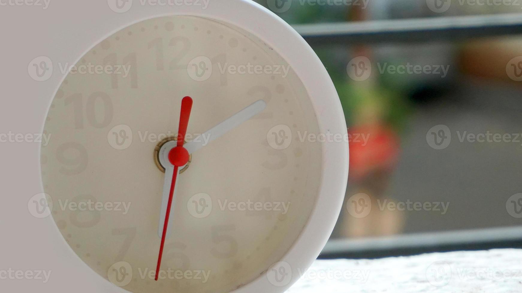 A closeup shot of a white clock with arrows showing time. photo