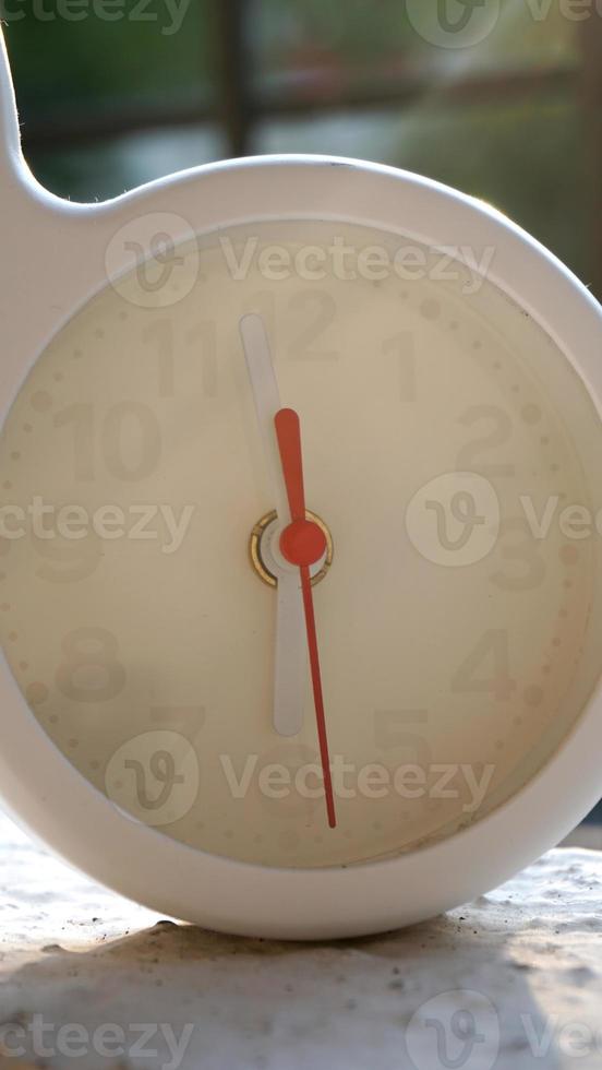 A closeup shot of a white clock with arrows showing time. photo