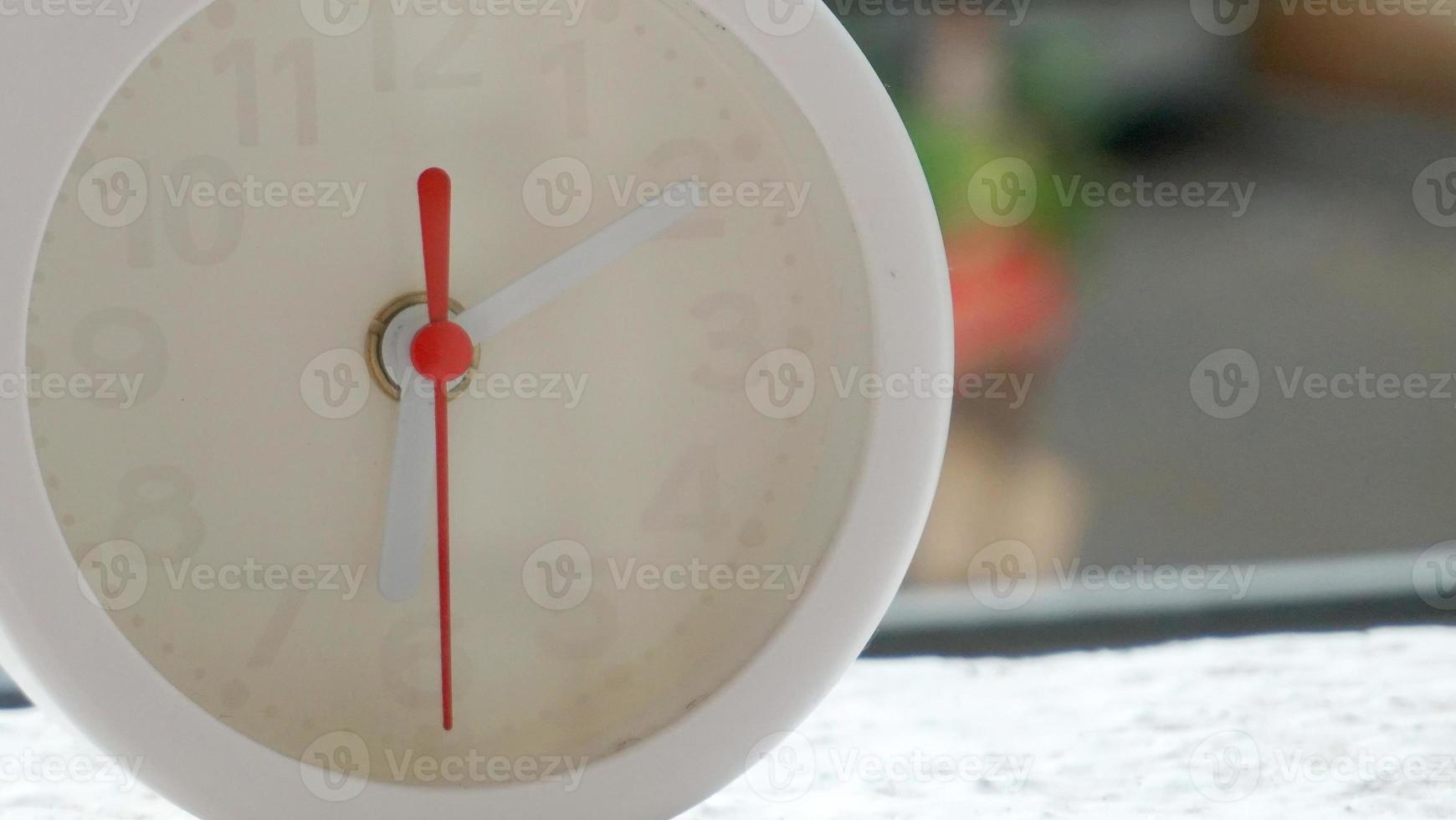 A closeup shot of a white clock with arrows showing time. photo