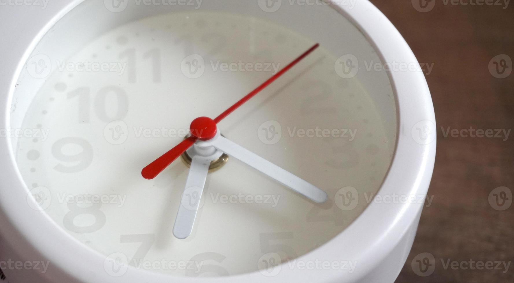 A closeup shot of a white clock with arrows showing time. photo