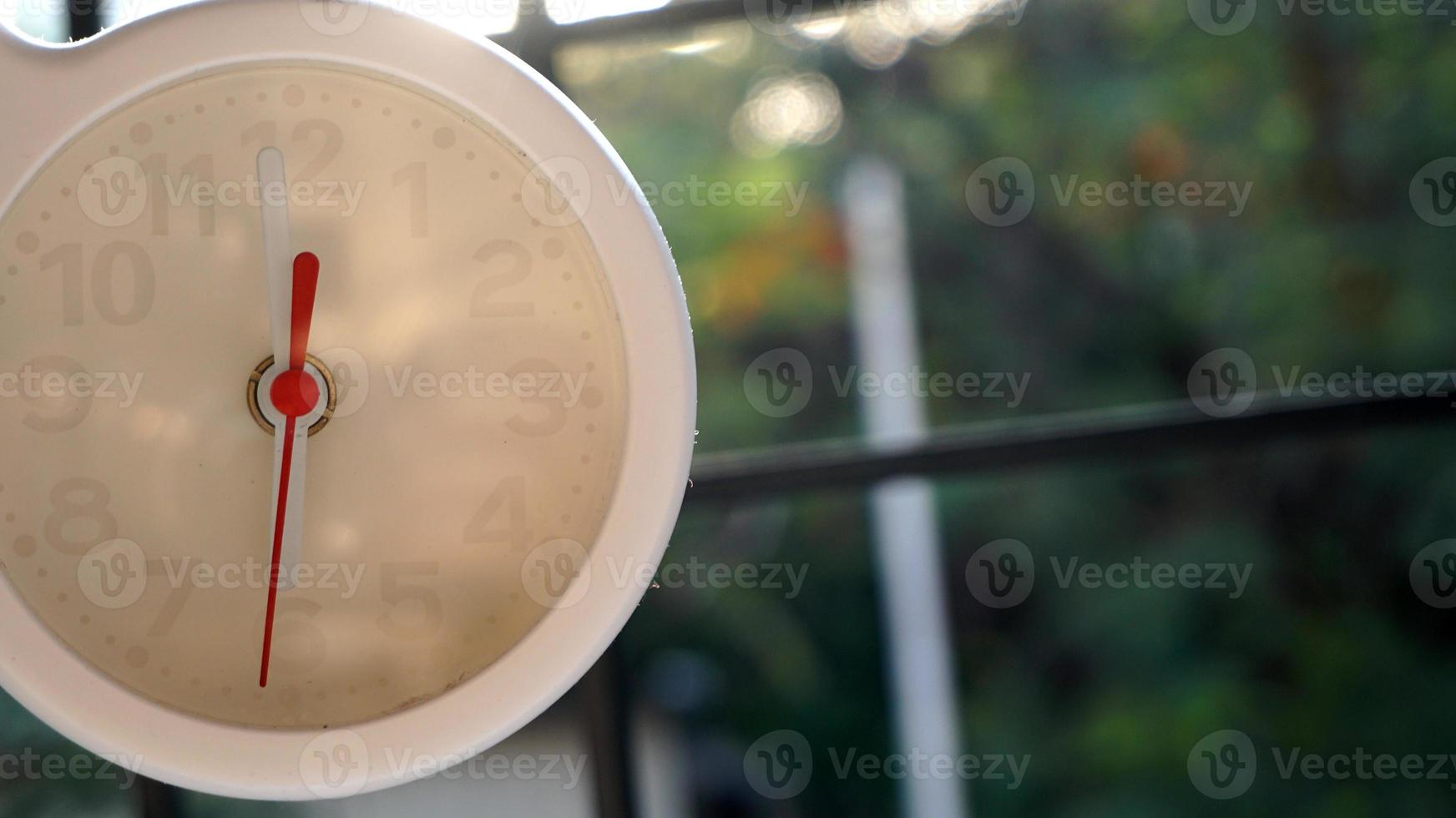 A closeup shot of a white clock with arrows showing time. photo