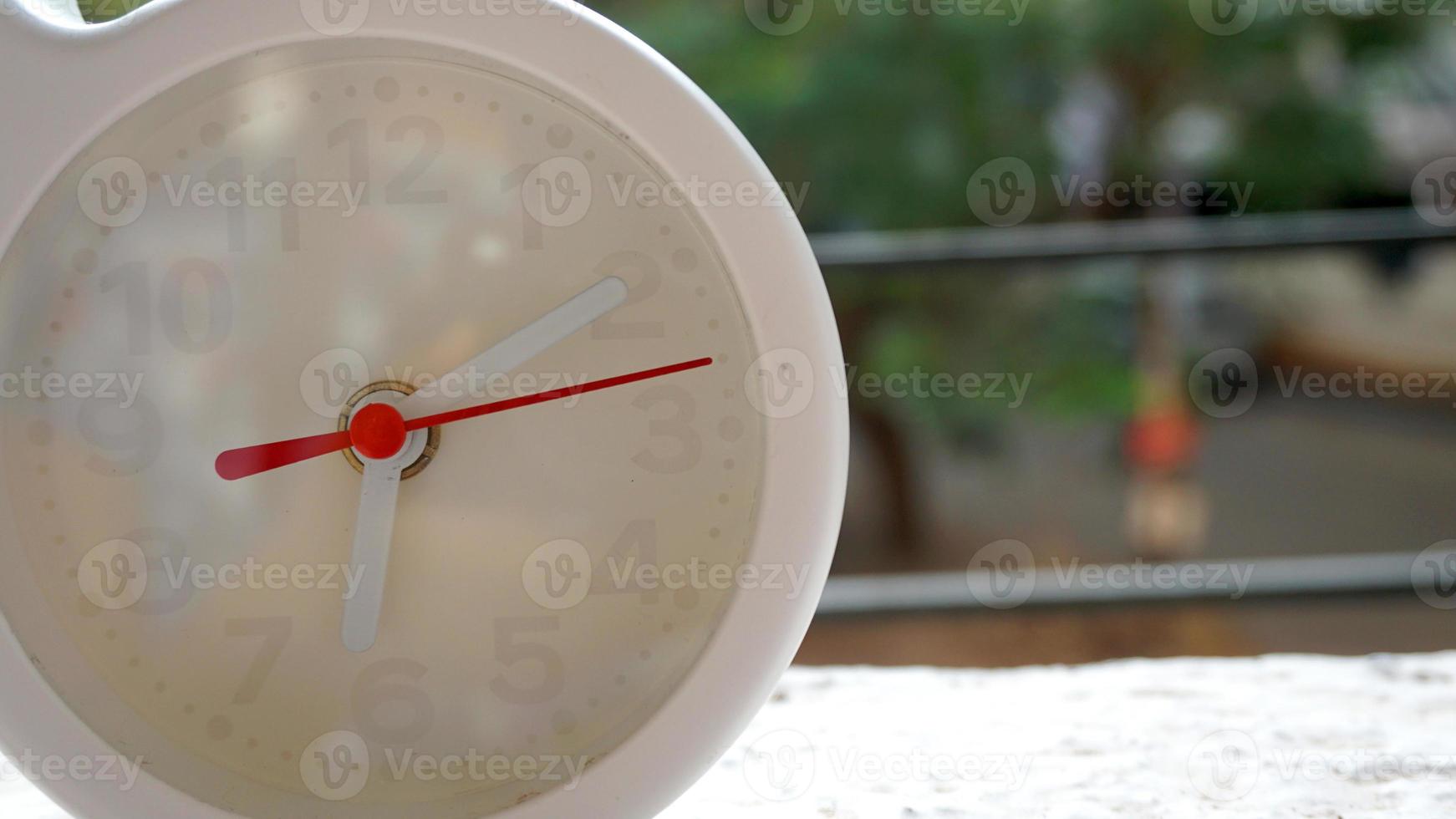 A closeup shot of a white clock with arrows showing time. photo