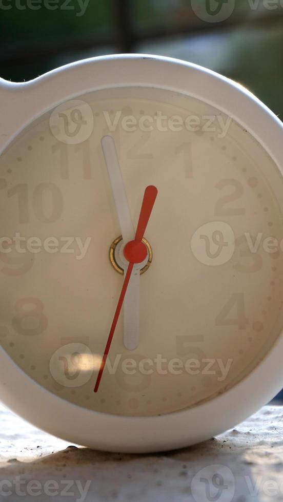 A closeup shot of a white clock with arrows showing time. photo