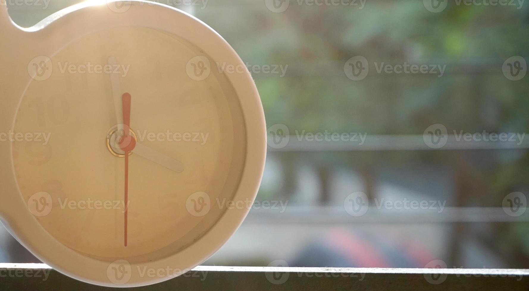 A closeup shot of a white clock with arrows showing time. photo