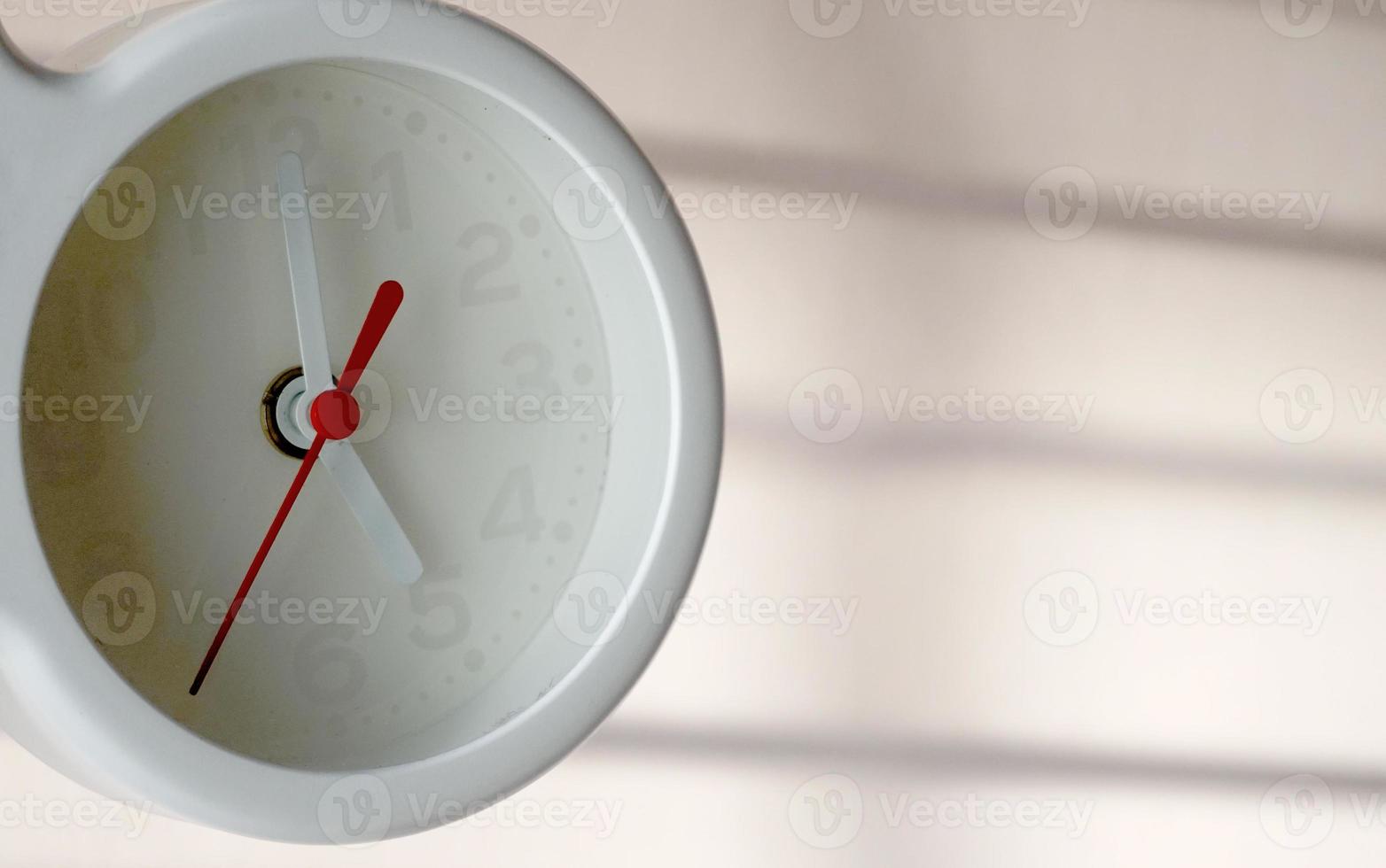 A closeup shot of a white clock with arrows showing time. photo