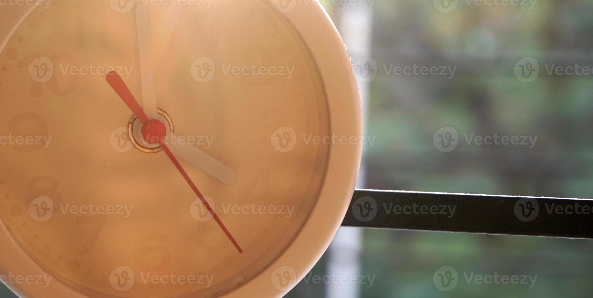 A closeup shot of a white clock with arrows showing time. photo