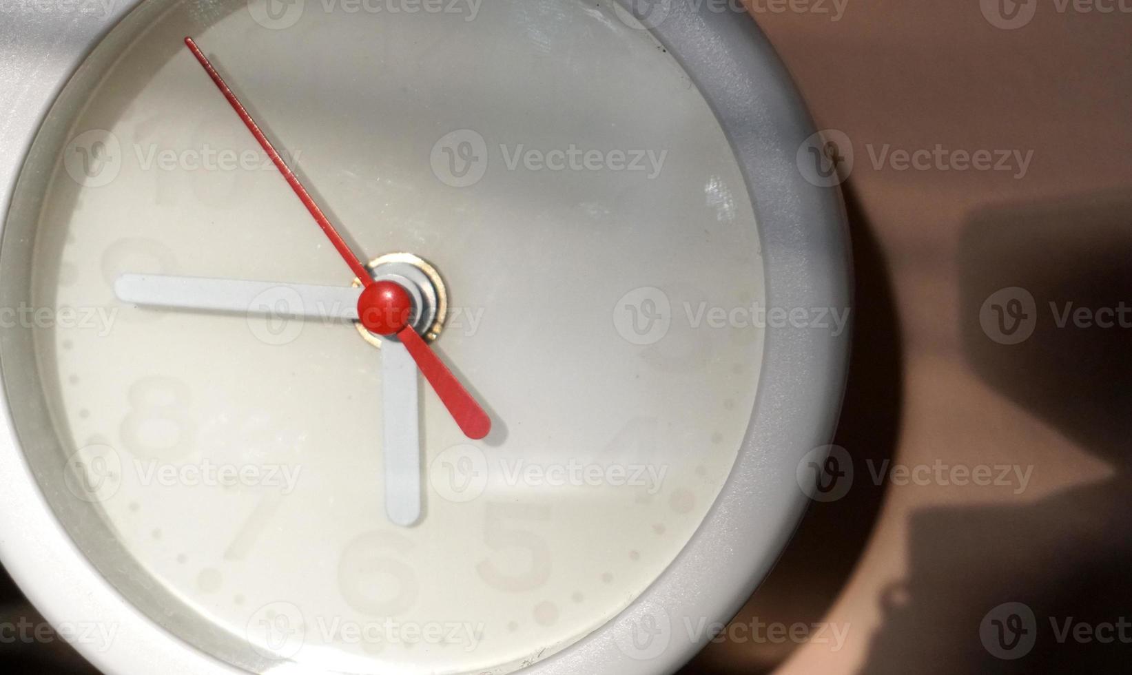 A closeup shot of a white clock with arrows showing time. photo