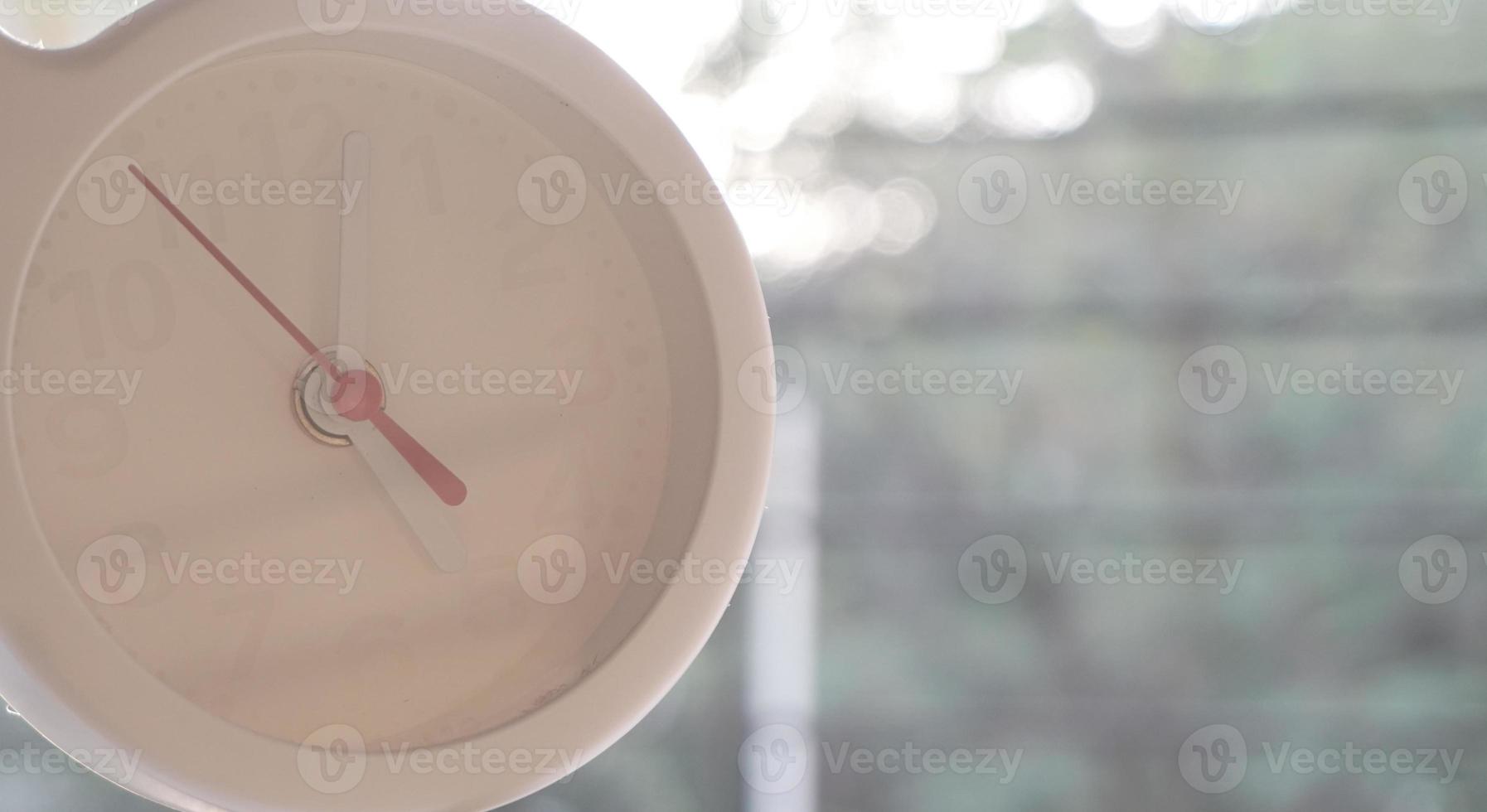 A closeup shot of a white clock with arrows showing time. photo