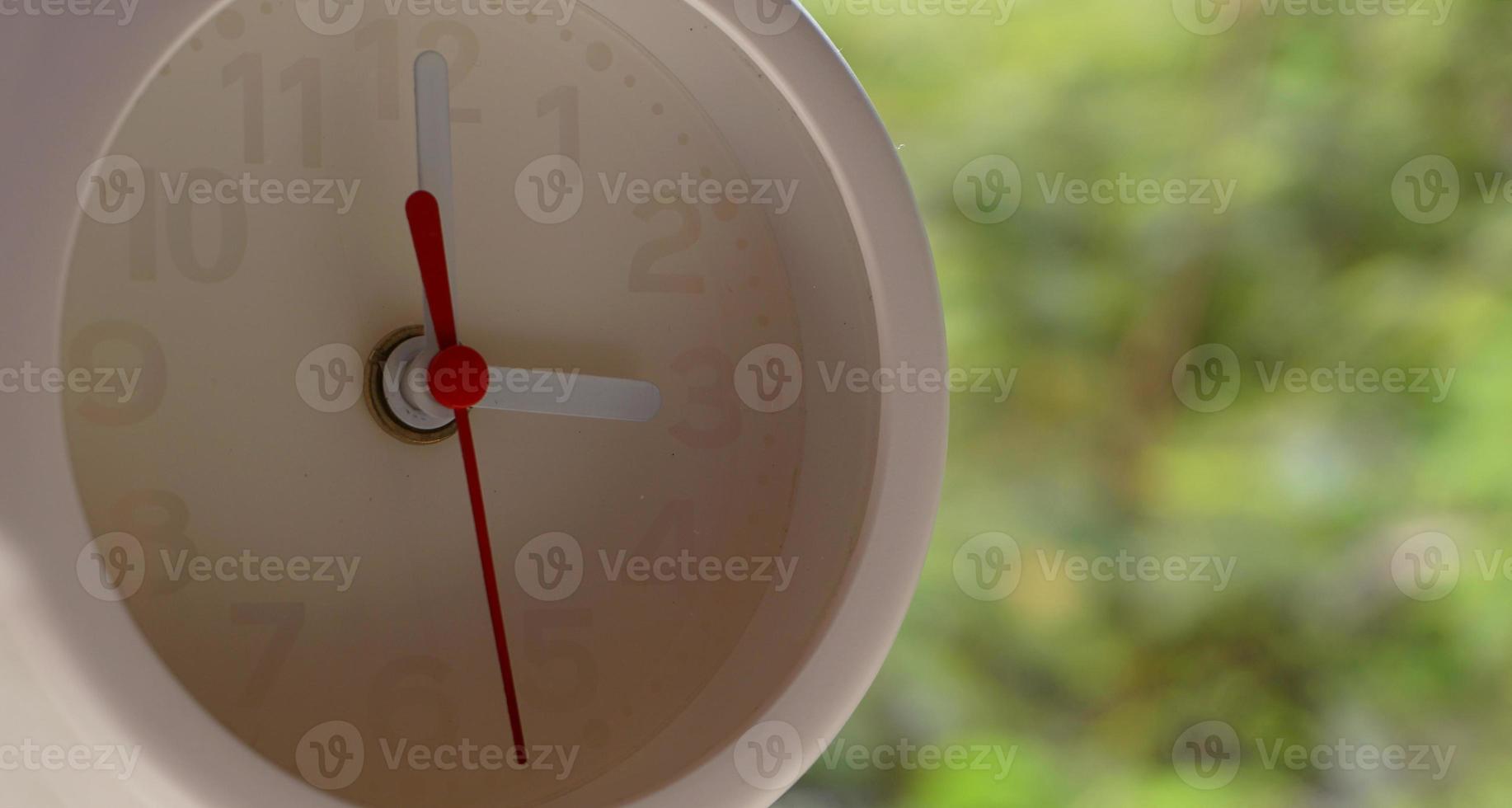 A closeup shot of a white clock with arrows showing time. photo