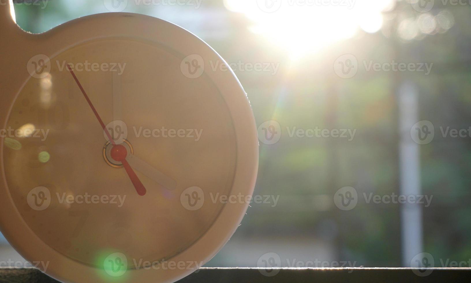 A closeup shot of a white clock with arrows showing time. photo