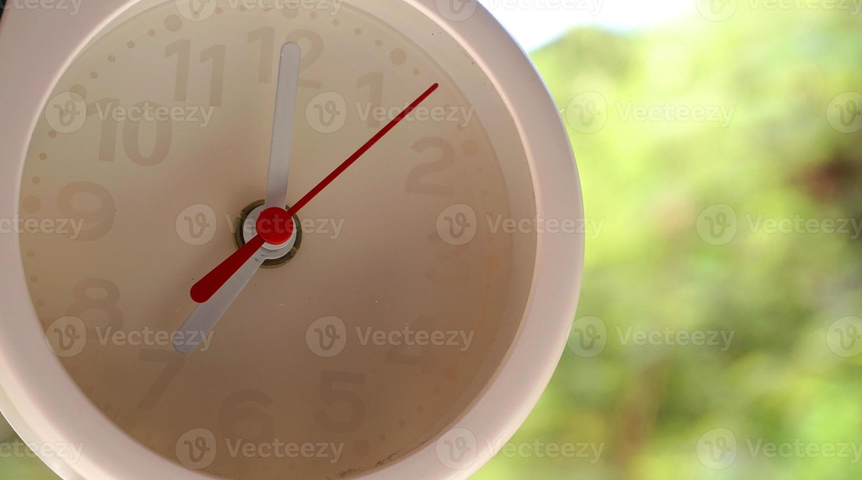 A closeup shot of a white clock with arrows showing time. photo