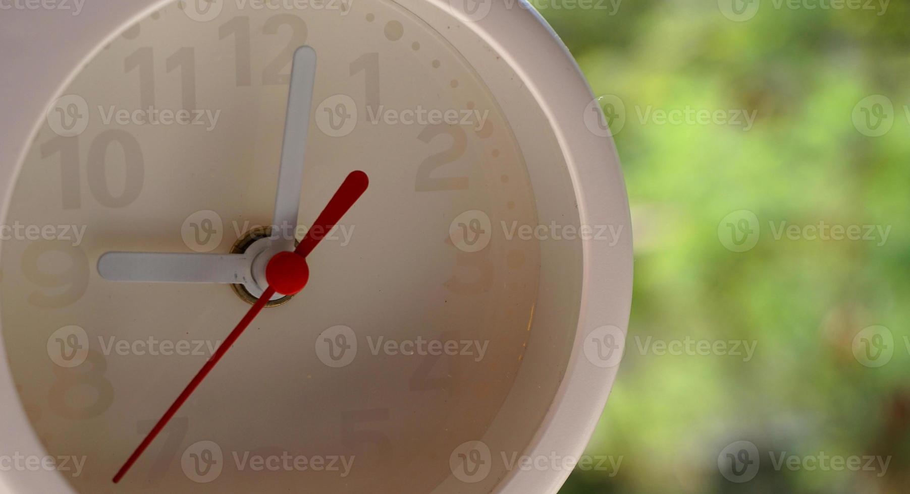A closeup shot of a white clock with arrows showing time. photo