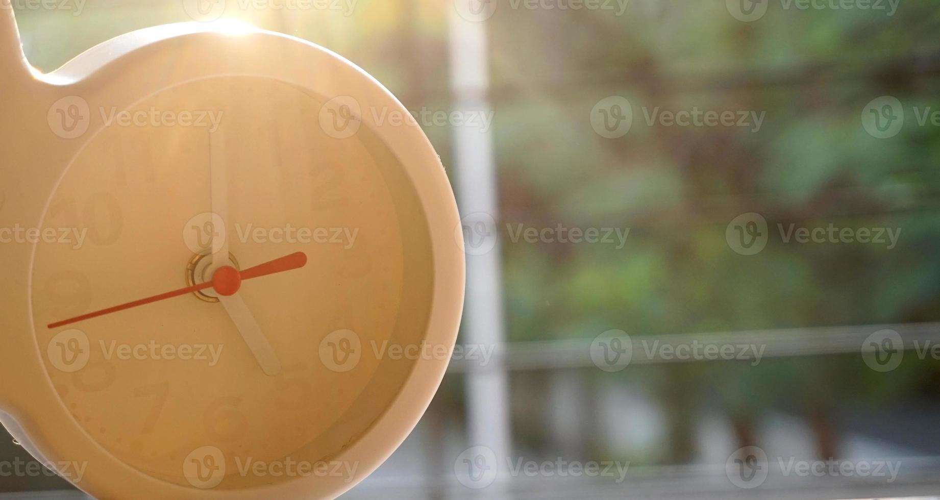 A closeup shot of a white clock with arrows showing time. photo