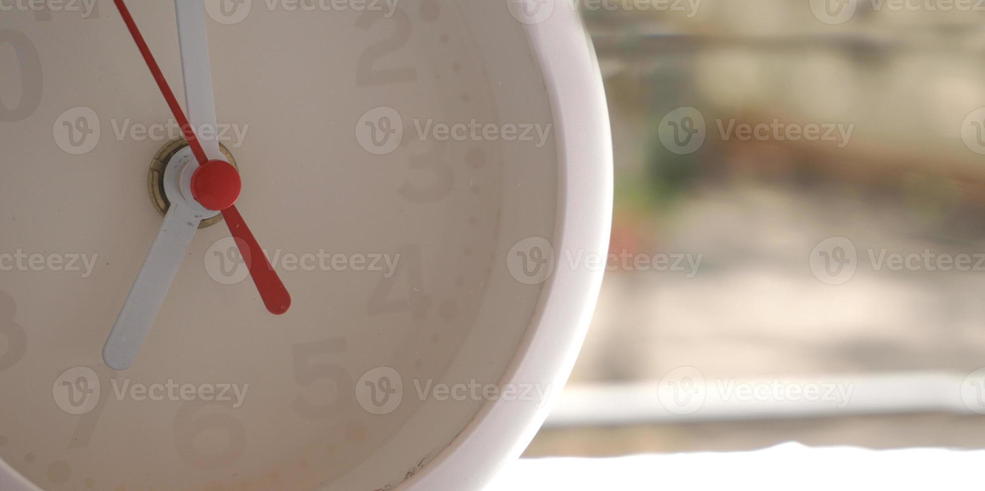 A closeup shot of a white clock with arrows showing time. photo