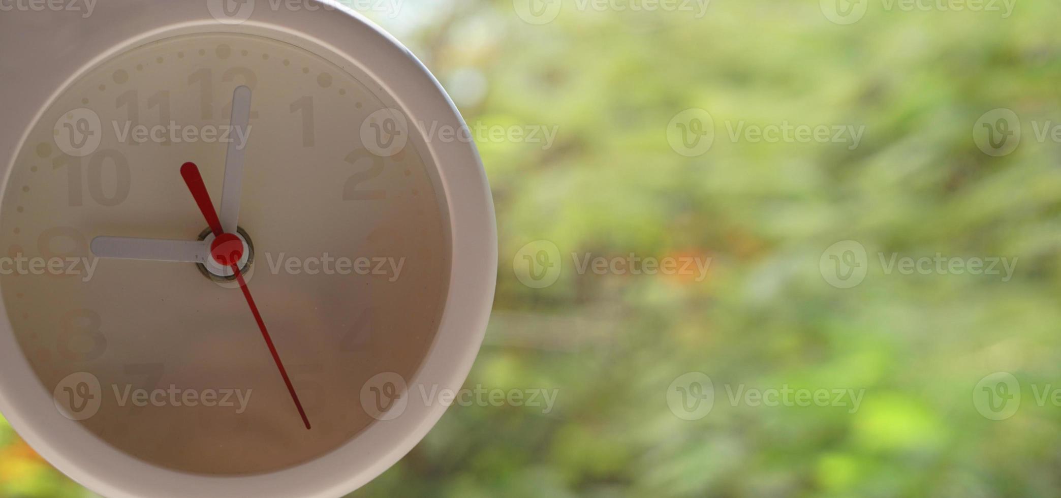 A closeup shot of a white clock with arrows showing time. photo