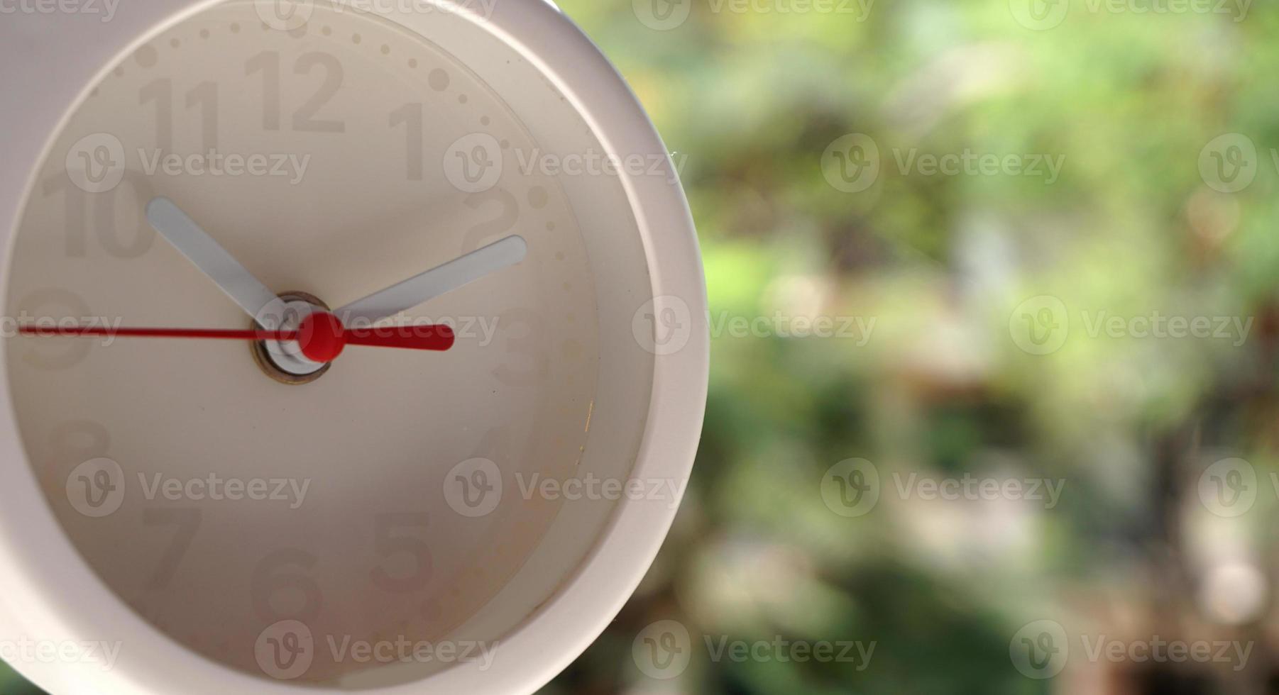 A closeup shot of a white clock with arrows showing time. photo