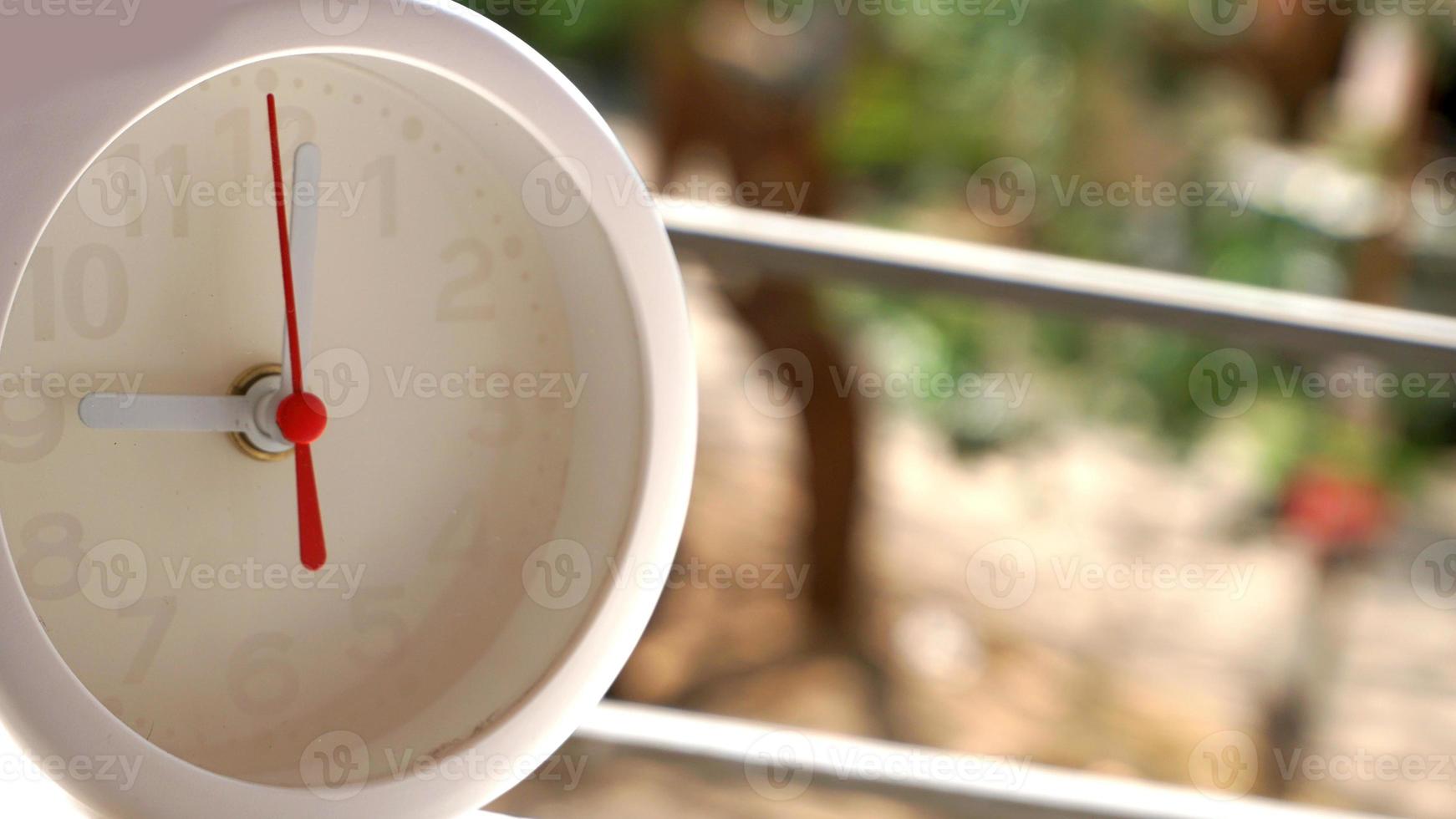 A closeup shot of a white clock with arrows showing time. photo
