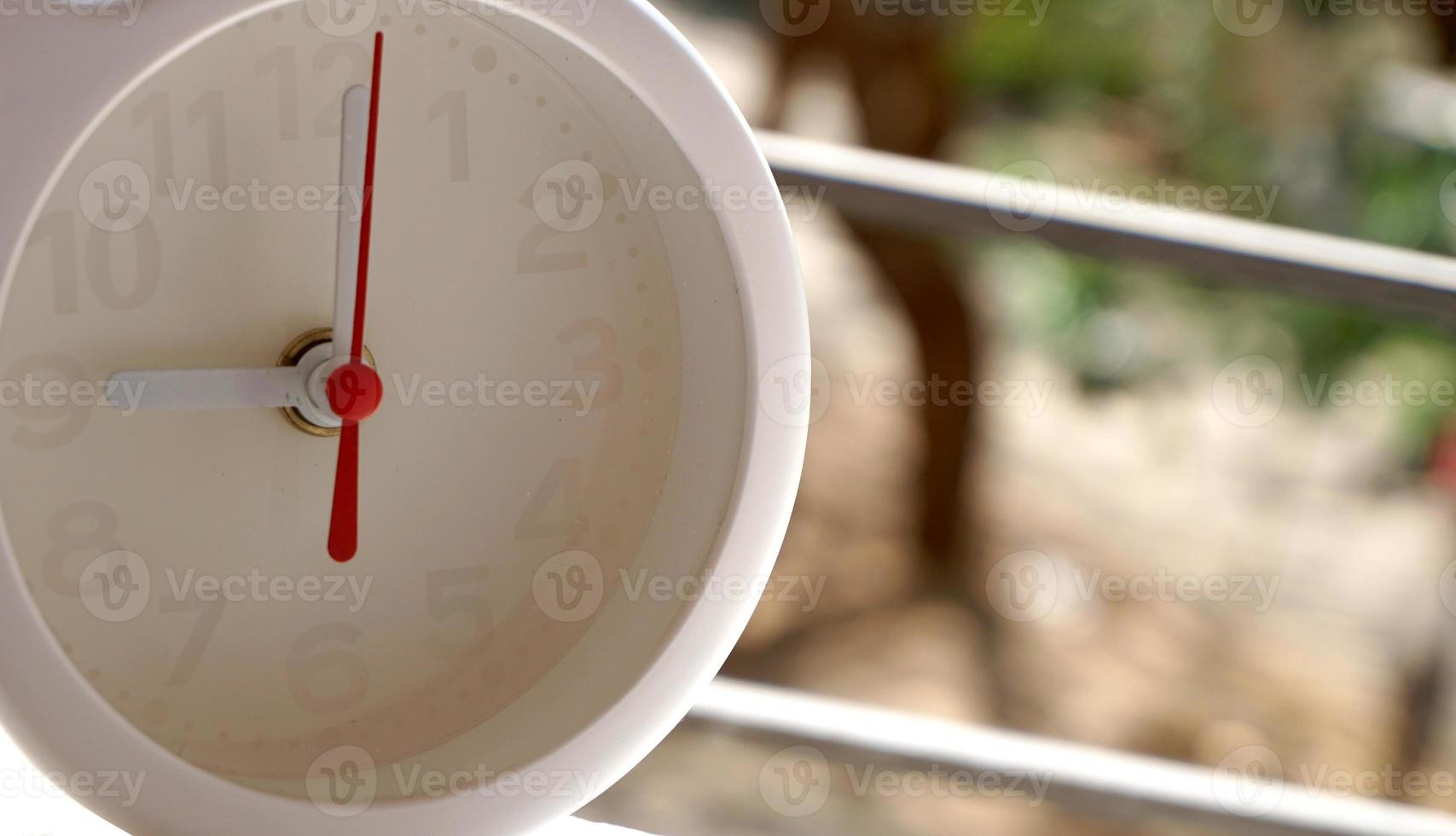 A closeup shot of a white clock with arrows showing time. photo