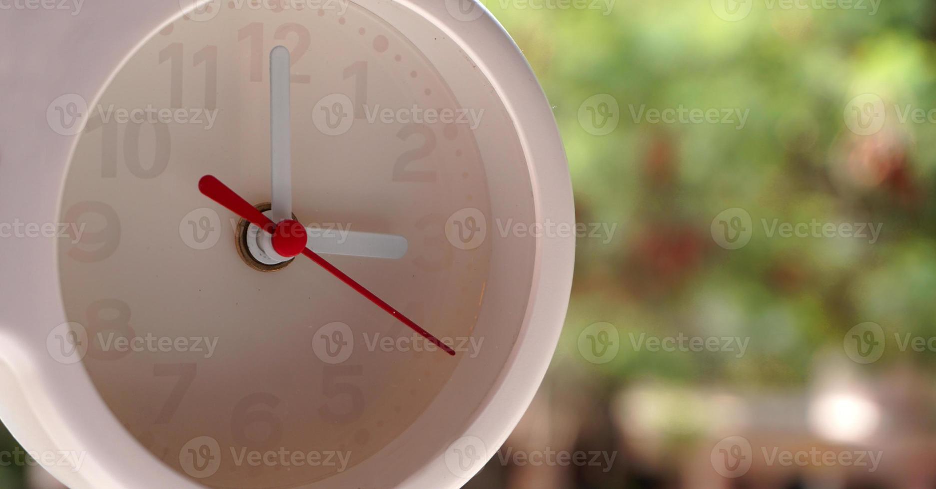 A closeup shot of a white clock with arrows showing time. photo