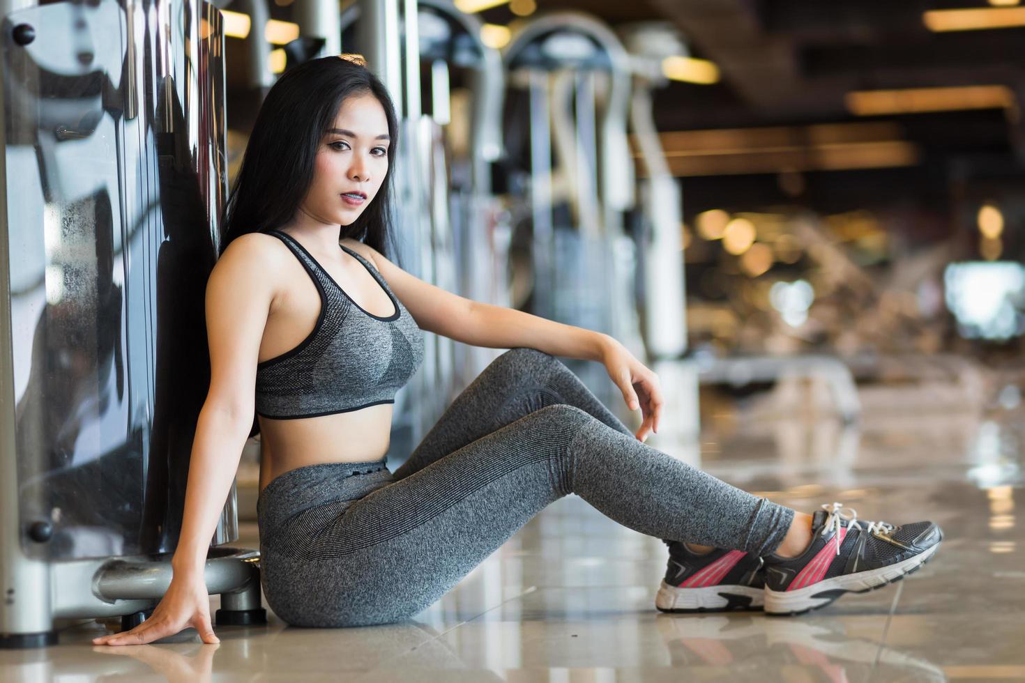 Fitness Asian women sitting in sport gym interior and fitness health club with sports exercise equipment Gym background. photo