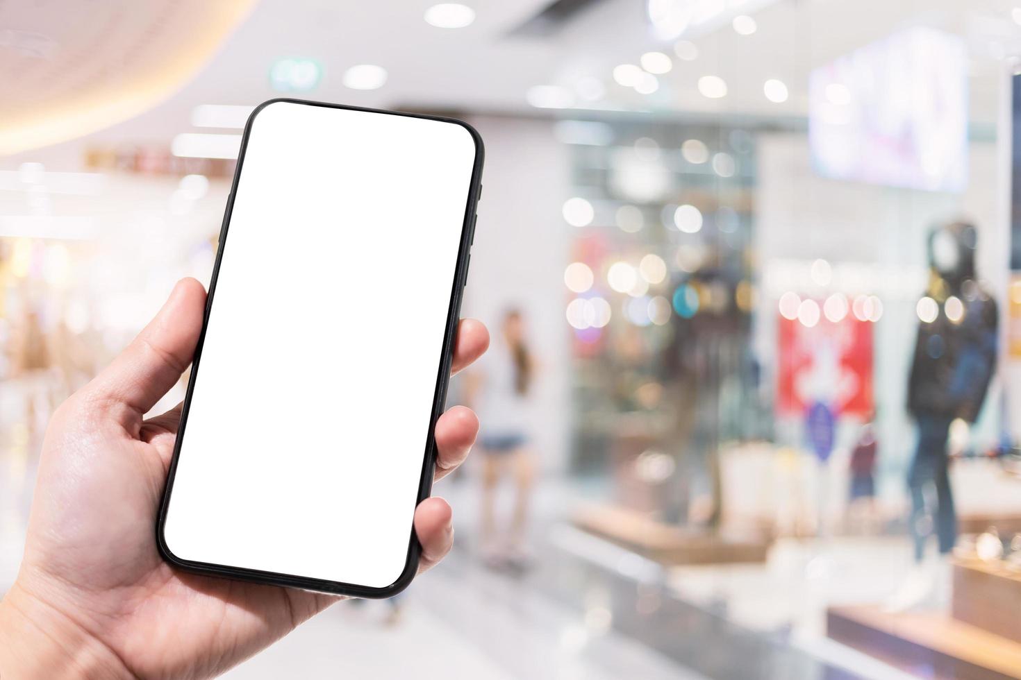 Primer plano de uso femenino smartphone borrosa imágenes en el centro comercial y tienda de ropa desenfoque del fondo. foto