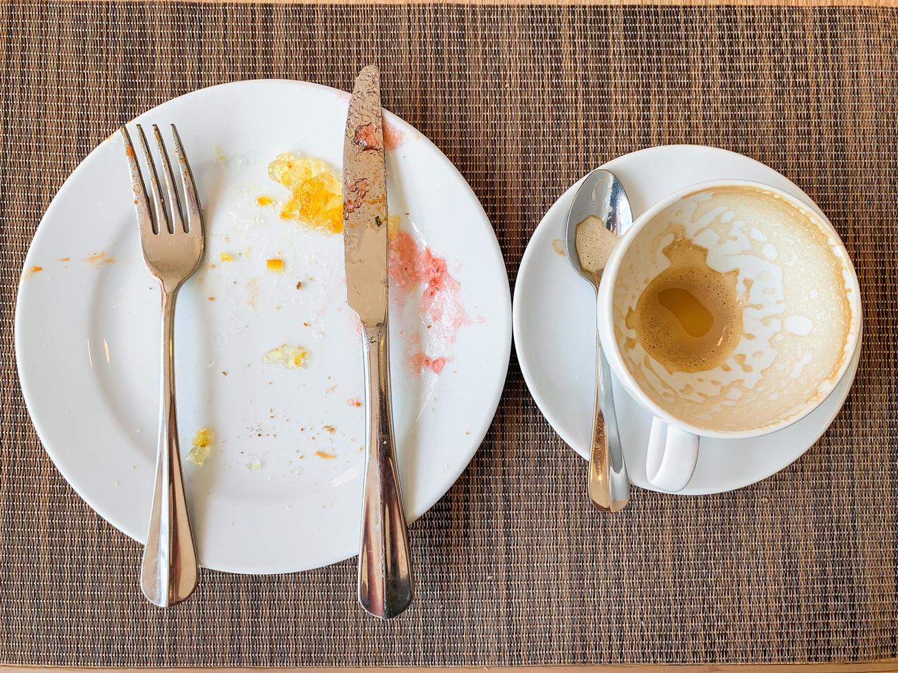 empty white dishes and coffee cup with after breakfast on wooden table. photo