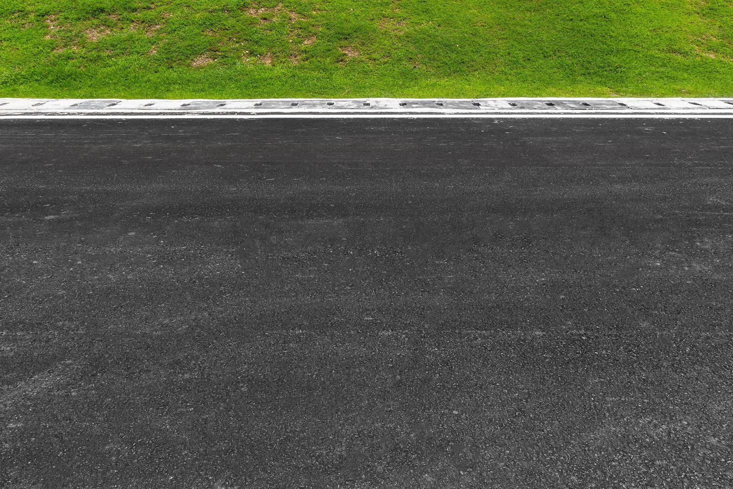 Carretera asfaltada con rayas y fondo de textura de hierba verde, espacio de copia vacío. foto