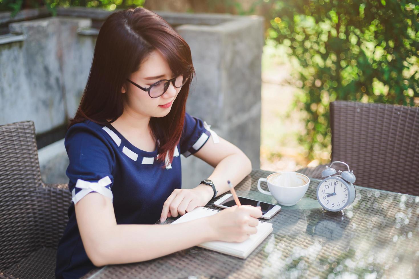 Asian young business woman between the thinking working make a note of something making and clock in summer park or office outdoor. photo