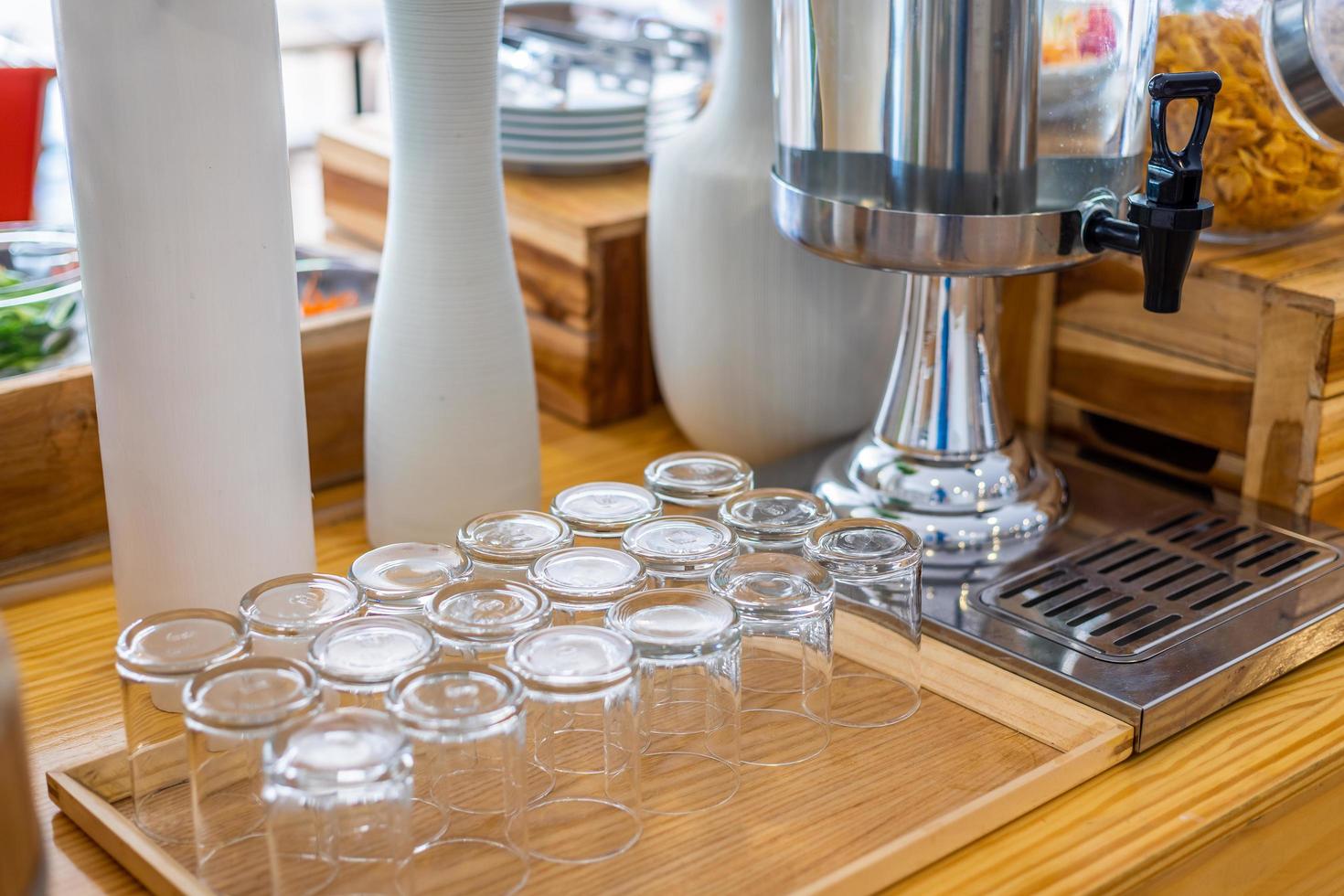 Varias filas de contenedores de botellas de vidrio vacías transparentes para agua fría en el buffet de autoservicio en el hotel. foto