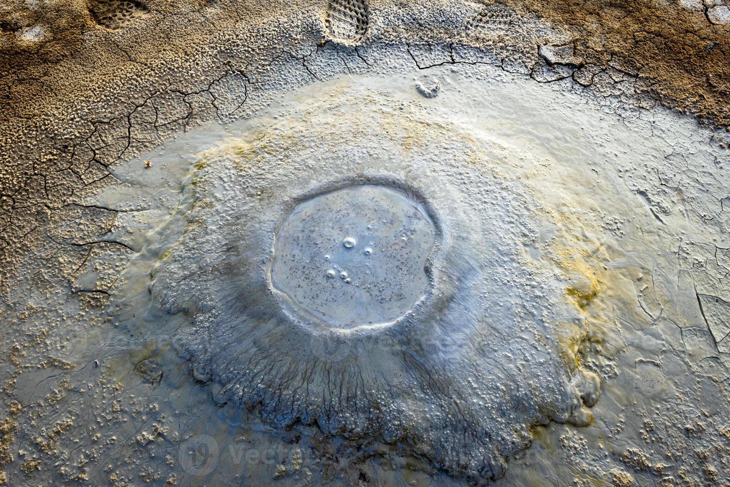 close up view down to small boiling mud volcanoe pond with colorful textures and pattern around photo