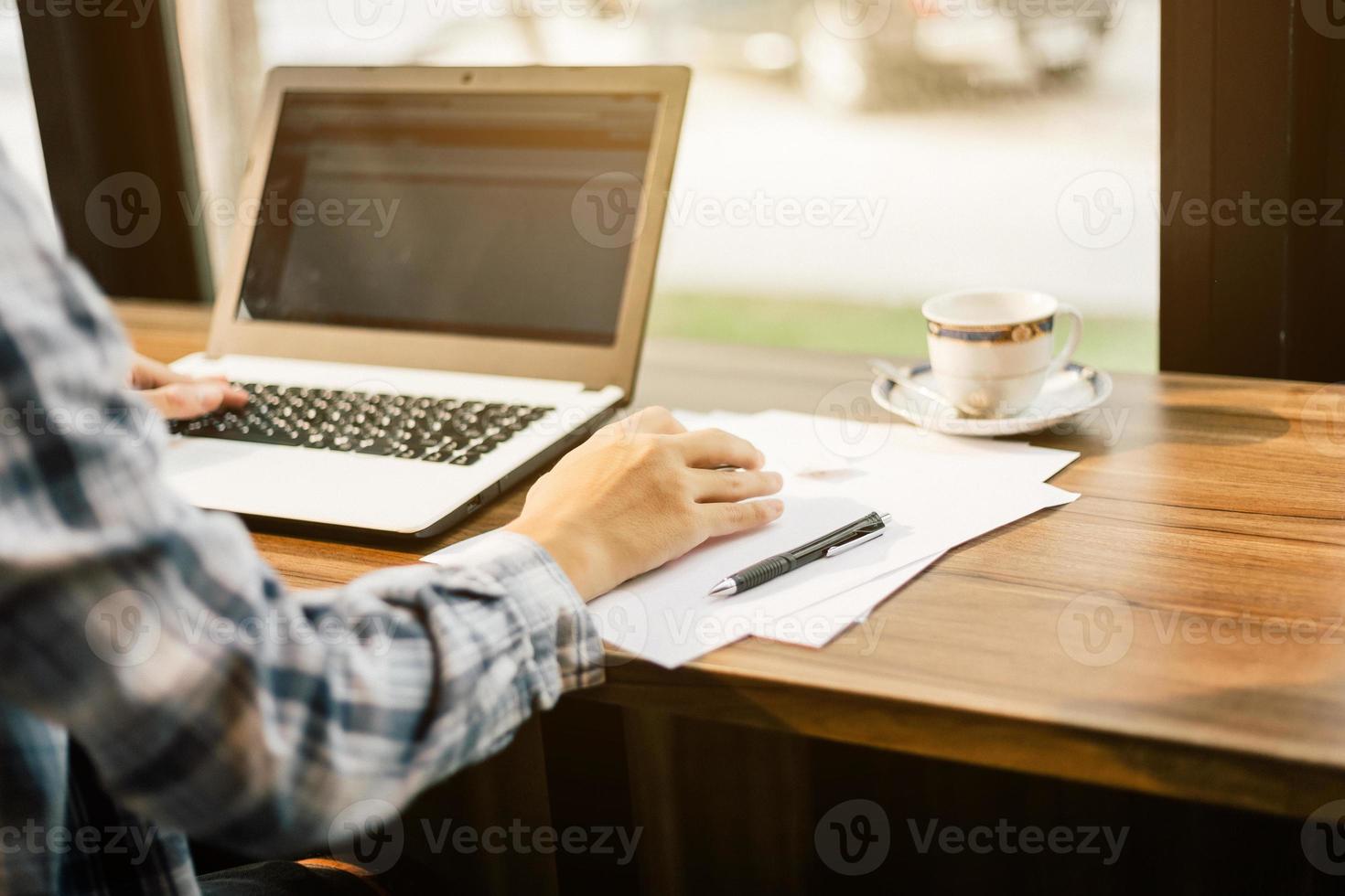 Close-up of businessman working with laptop computer on in coffee shop like the background. photo