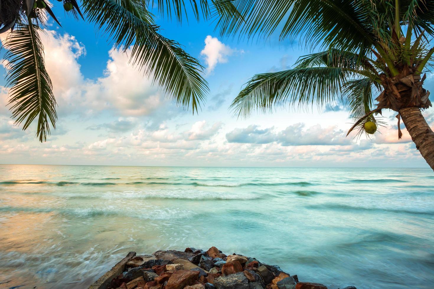 hermoso amanecer temprano en la mañana sobre el cocotero con el mar el horizonte en la playa de hat chao lao en chanthaburi, tailandia. foto