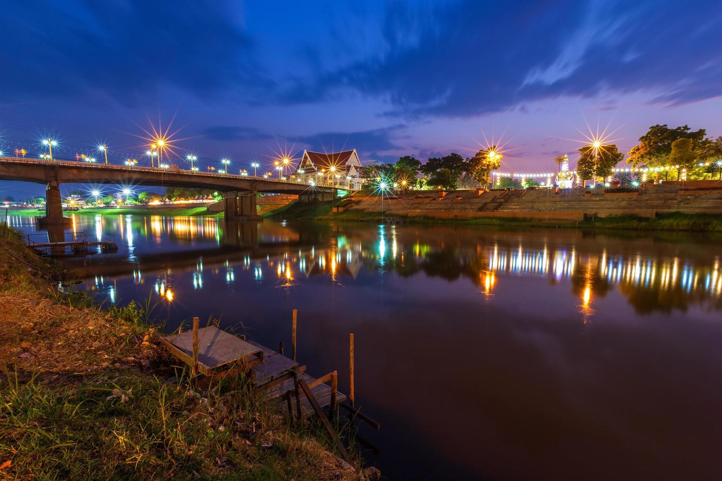 hermosa luz sobre el río nan en la noche en el puente puente naresuan en la ciudad de phitsanulok, tailandia. foto
